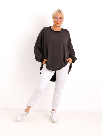 Silberstern Oversize-Sweater CARLY.S in Braun mit Inside-Out-Nähten, kombiniert mit weißer Hose und Sneakern.