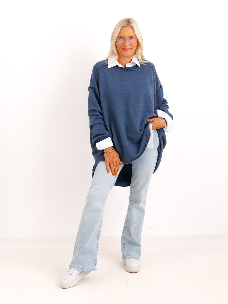 Silberstern Oversize-Sweater CARLY.S in Dunkelblau mit Inside-Out-Nähten, kombiniert mit heller Jeans und weißem Hemd.