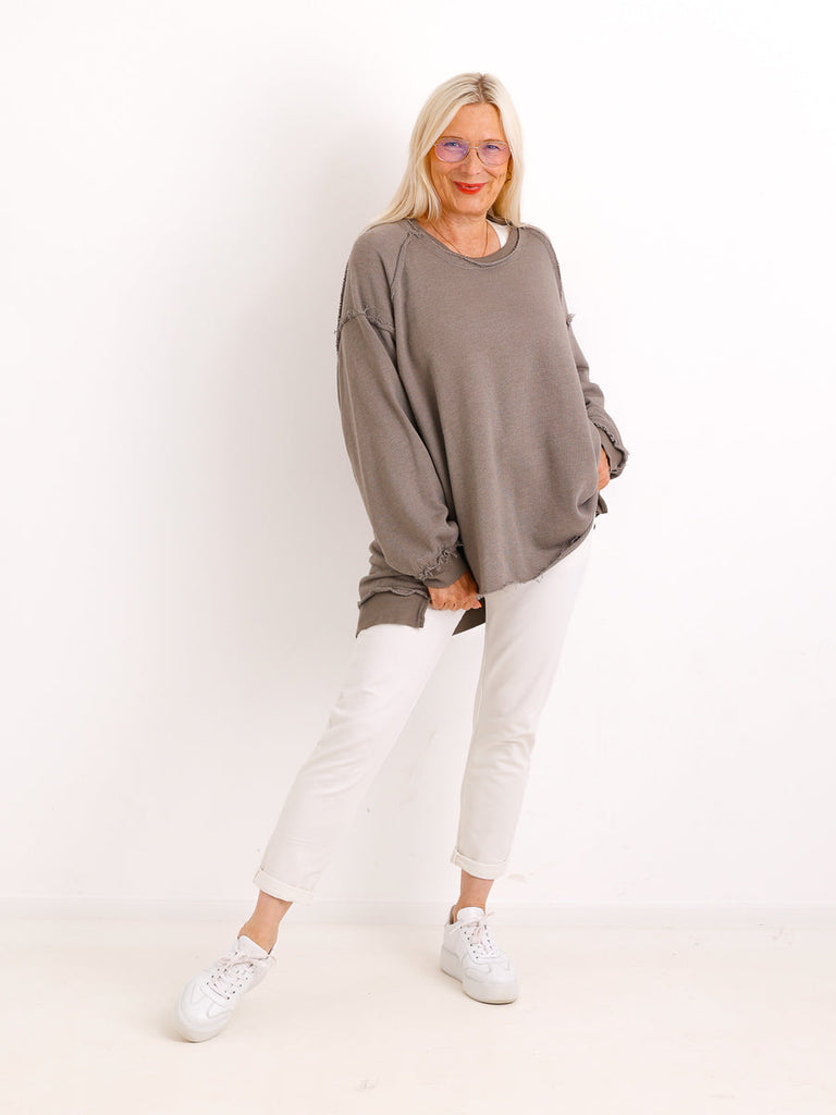 Silberstern Oversize-Sweater CARLY.S in Taupe mit Inside-Out-Nähten, getragen von einem Model mit weißer Hose.